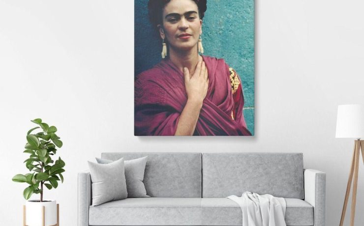 Modern living room with grey sofa and white walls, featuring bold Frida Kahlo Wall Art portrait above the couch.