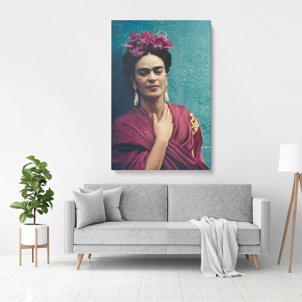 Modern living room with grey sofa and white walls, featuring bold Frida Kahlo Wall Art portrait above the couch.