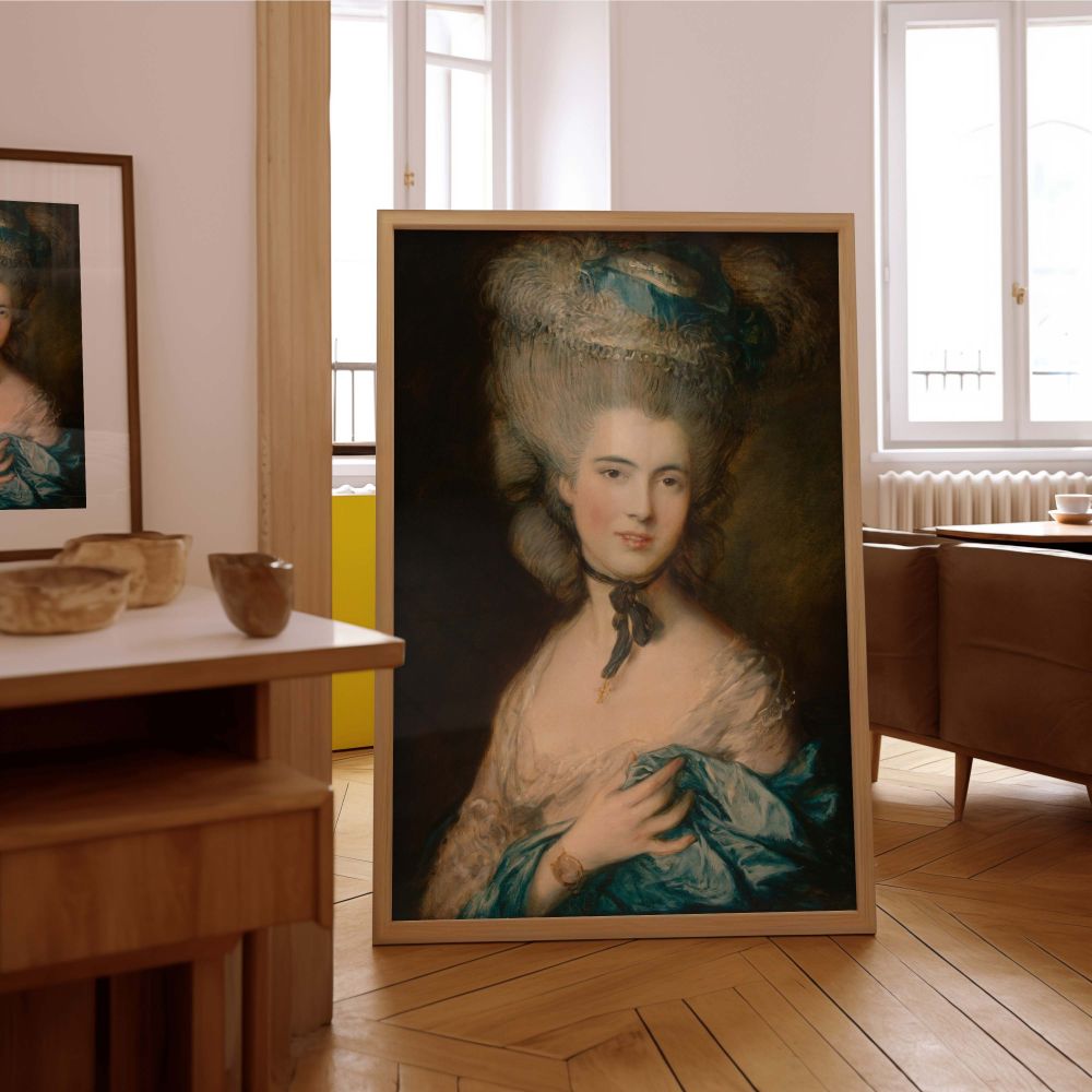 Rococo-style portrait featured as a wall canvas, painted by Thomas Gainsborough. The sitter wears a luxurious blue dress with detailed lace and a bold, voluminous hairstyle typical of the 1700s. Her skin glows with soft light, and her hand rests delicatel