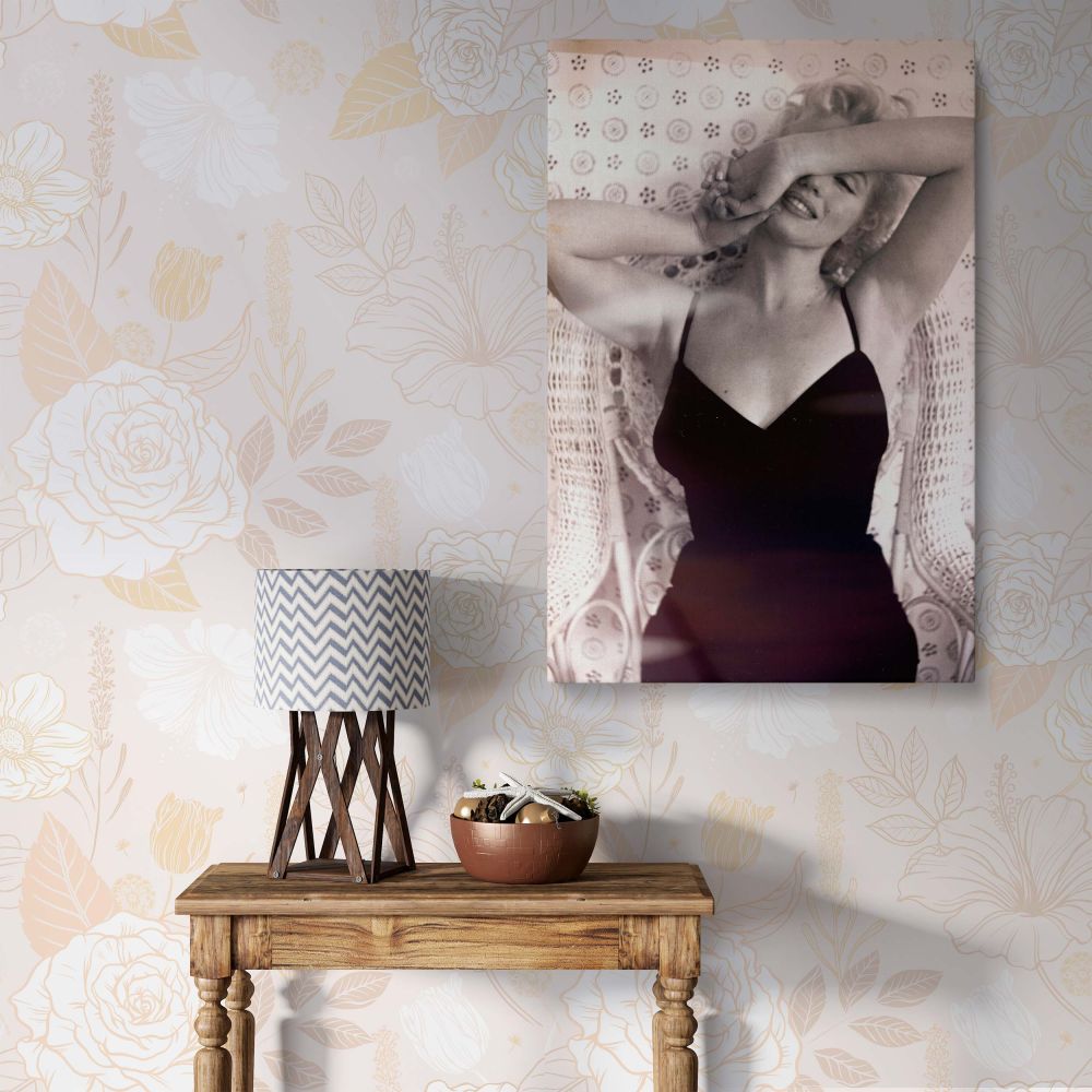 Marilyn Monroe striking a pose in a classic black dress with a flirtatious smile and vintage wicker chair, ideal retro actress print wall art.