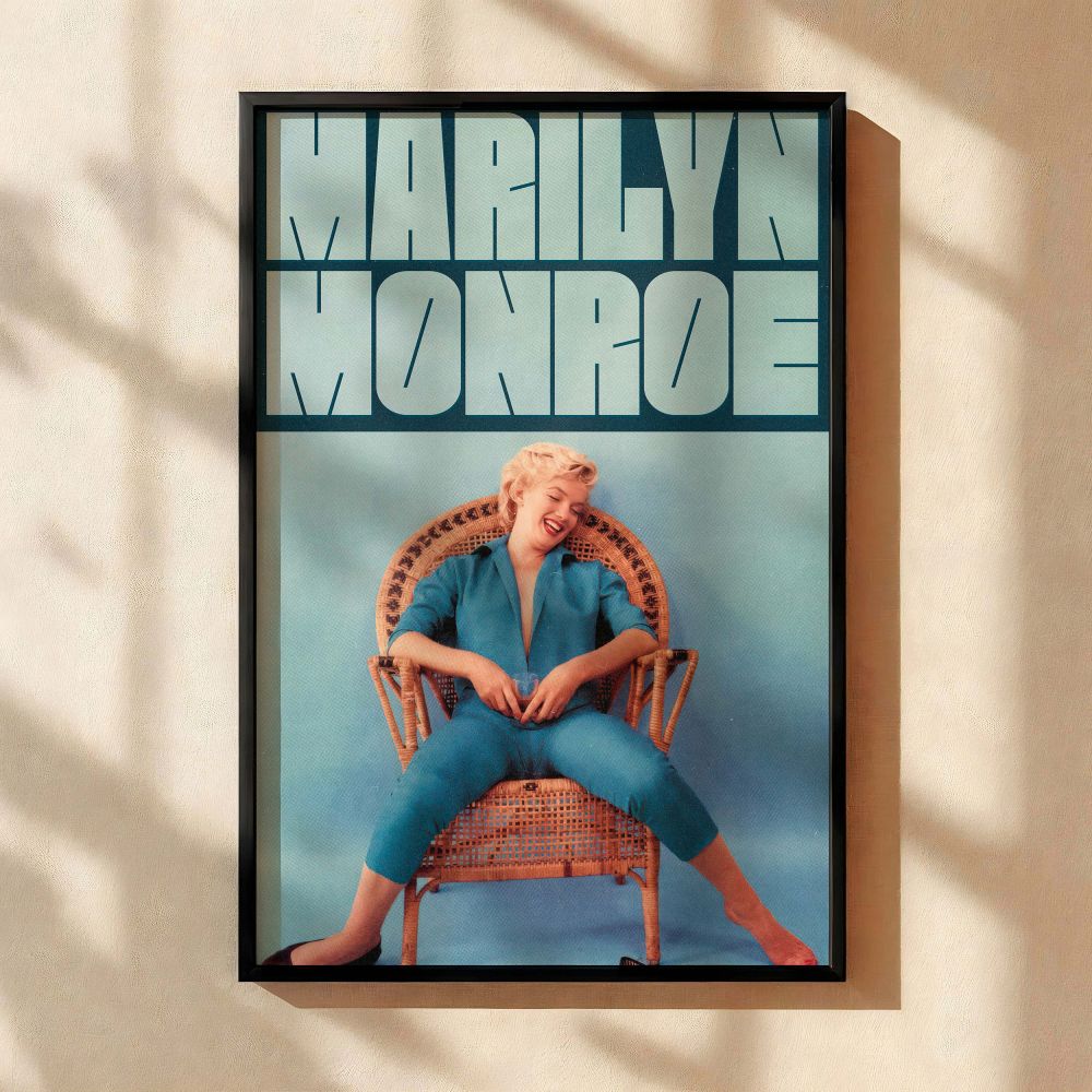This Marilyn Monroe photo print shows her barefoot and joyful in a bright blue jumpsuit sitting casually in a wicker chair set against a blue backdrop capturing her vintage charm and relaxed Hollywood fashion for retro home decor.