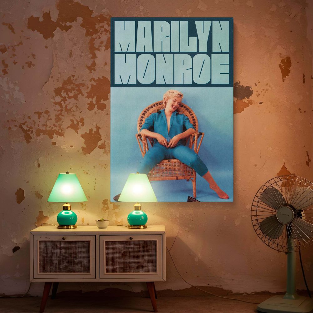 Marilyn Monroe in a casual retro setting wearing a stylish blue jumpsuit sitting joyfully in a vintage rattan chair brings classic Hollywood energy and timeless beauty to walls in homes studios or fashion-themed spaces.