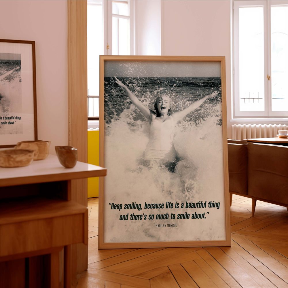 Glamorous black and white image of Marilyn Monroe caught mid-laugh in the ocean with her timeless quote about smiling showcasing her fun side perfect for inspirational gallery walls or personal growth themed decor.