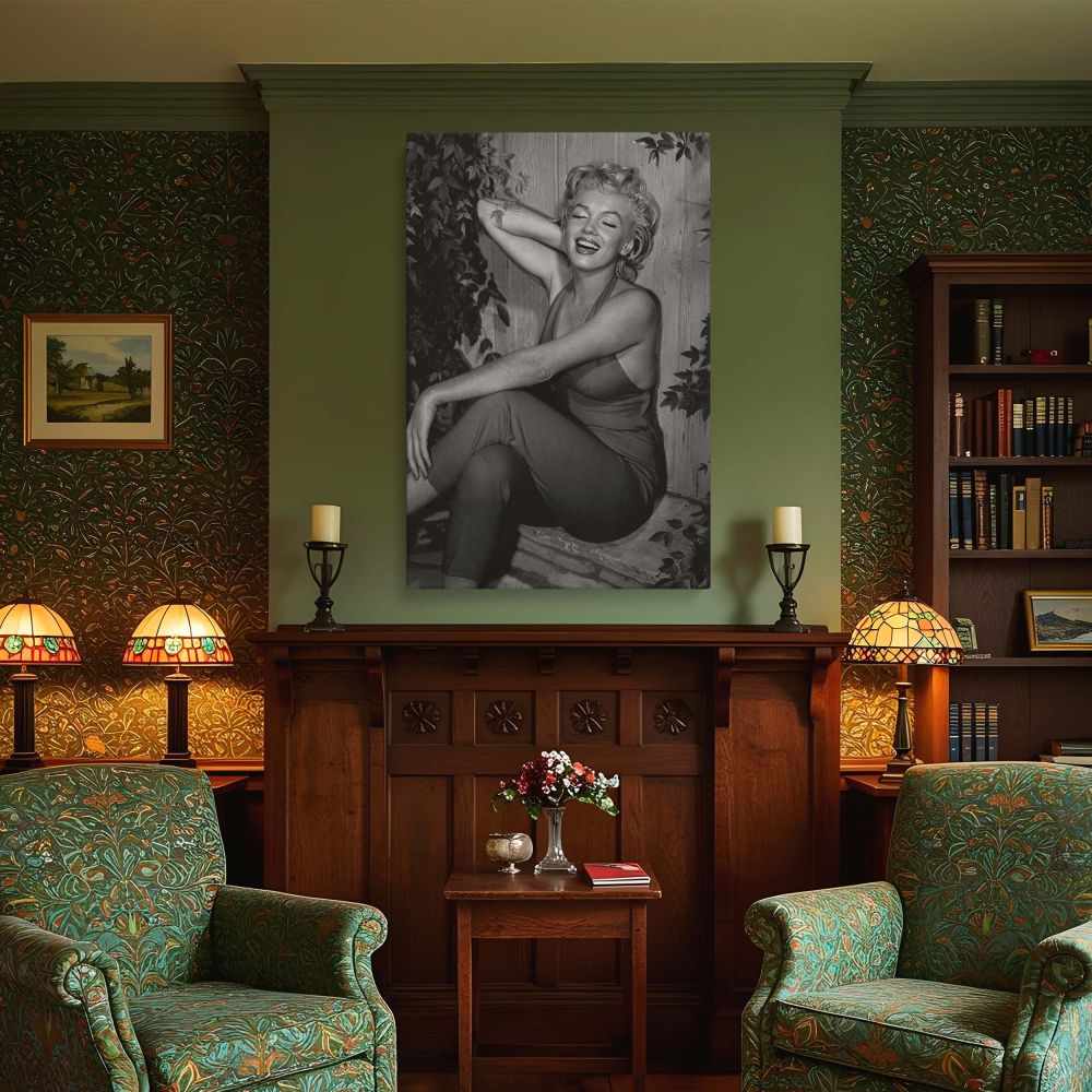 Marilyn Monroe is seen glowing in a candid black and white photograph sitting with joy in her red jumpsuit surrounded by foliage making this the perfect glamorous photo print for vintage home decor and Hollywood legend enthusiasts.