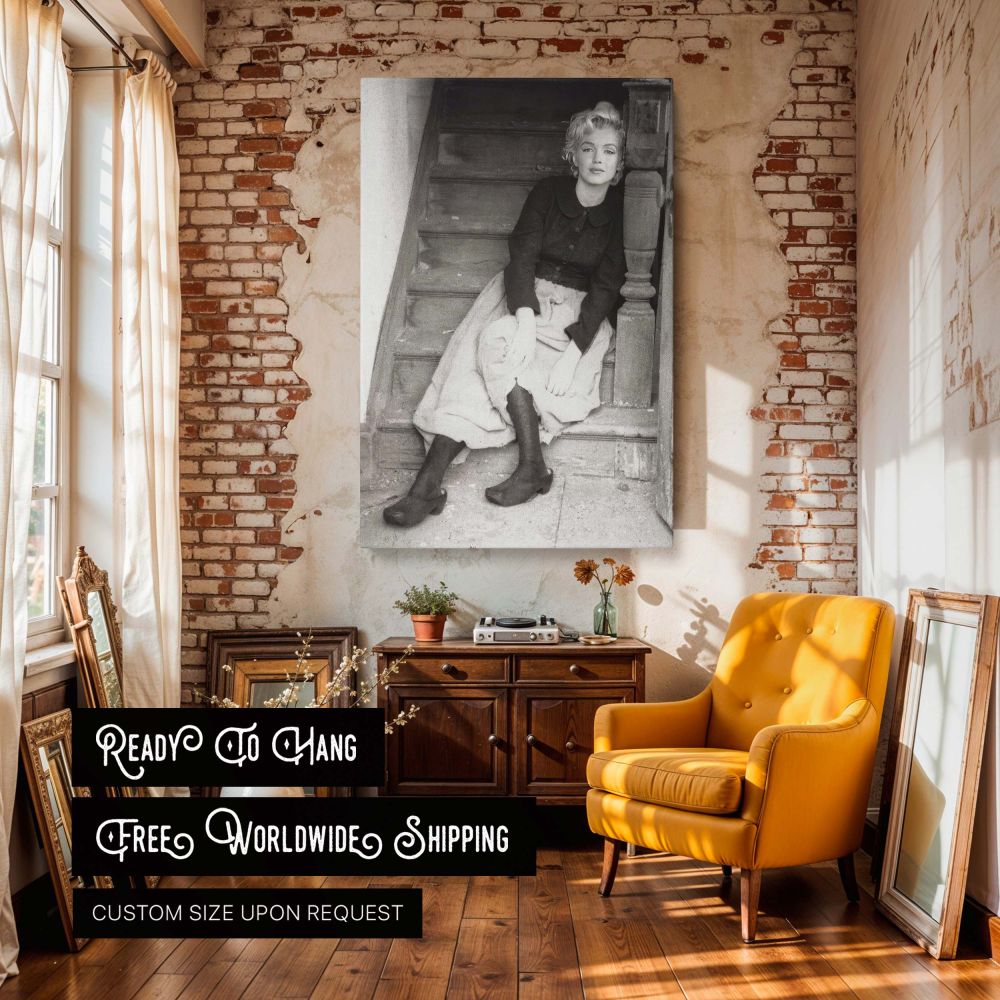 Black and white portrait of Marilyn Monroe leaning against staircase railing in vintage outfit captures the essence of classic femininity and rustic simplicity ideal as timeless wall art decor for Hollywood history admirers.
