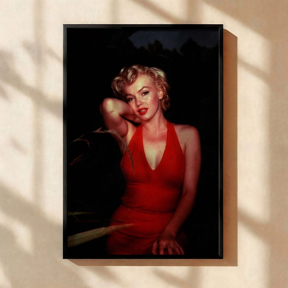 A captivating vintage fashion photo of Marilyn Monroe wearing a bold red dress with her arm resting against her head set against a dark moody backdrop this Hollywood wall art reflects her status as an iconic actress and is perfect for collectors who adore