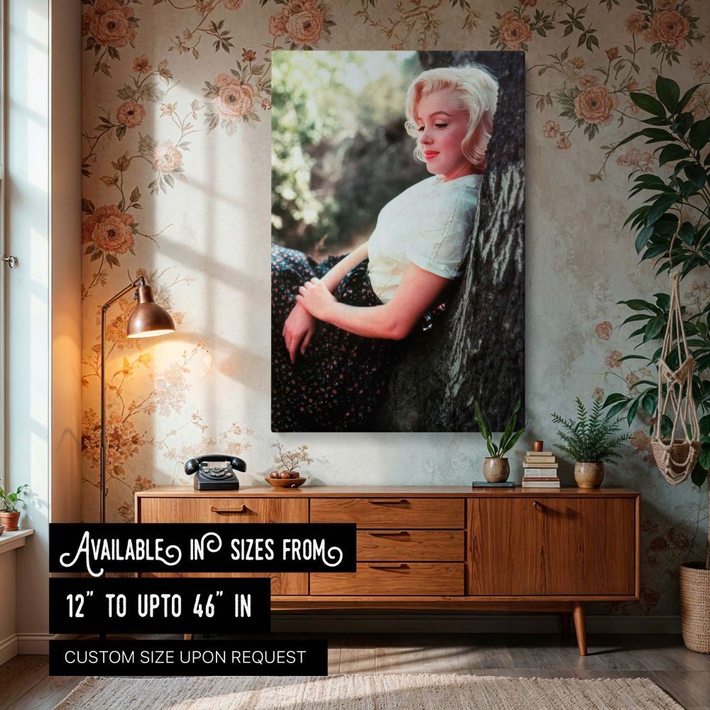 This vintage wall art features Marilyn Monroe in a soft and peaceful moment leaning against a tree dressed in a white blouse and floral skirt embodying the timeless essence of Hollywood glamour captured in a rare outdoor canvas print perfect for fans of c
