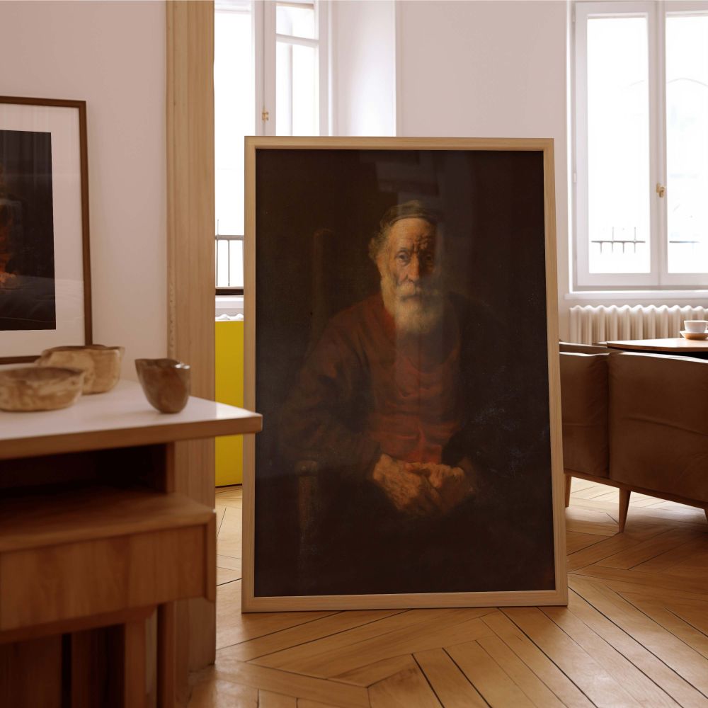 Rembrandt's masterful portrait of an old man in a red garment captured in this canvas wall print features strong chiaroscuro, gentle lighting, and a somber expression. The soft modeling of light across the face and robe adds visual interest and historical