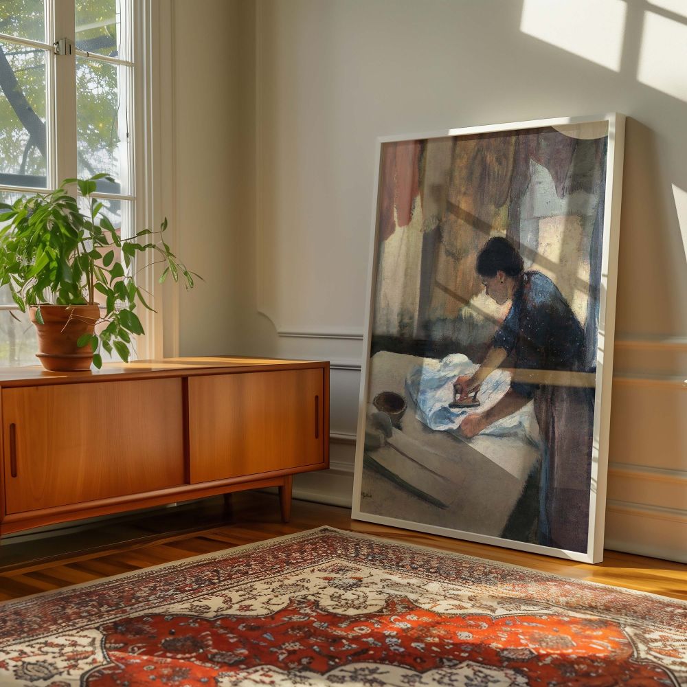 Canvas wall art of a domestic interior from Woman Ironing by Edgar Degas, where a focused woman in a blue blouse and apron presses linen in a softly lit room. The composition is framed by drying clothes and shadows that suggest late afternoon light. This 