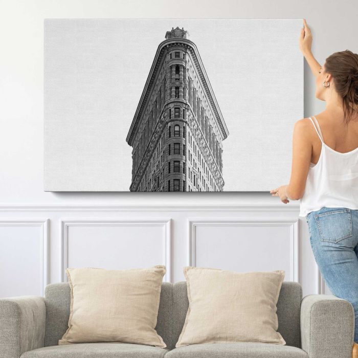 Black and white photo looking up at the Flatiron Building in New York City canvas print, canvas shown with a person for scale