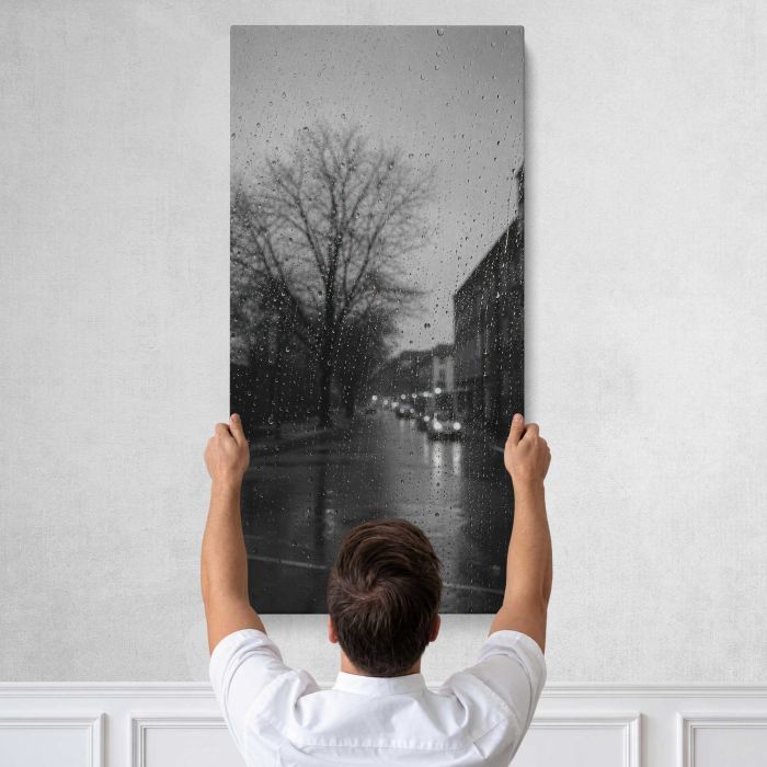 Rainy city street through window droplets, moody monochrome canvas print, tall canvas held against a wall