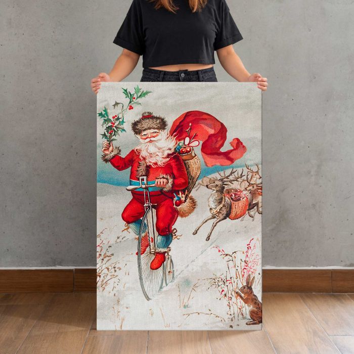 Santa Claus on a Penny Farthing with Reindeer and Rabbit canvas print, canvas shown with a person for scale