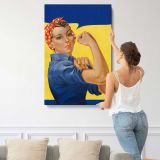 Woman Flexing in Blue Workwear canvas print, displayed on a wall